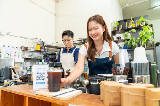Female barista serving fresh iced coffee to customer at cafe counter, professional beverage drink preparation specialty coffee and tea shop, small business hospitality and takeaway drink service