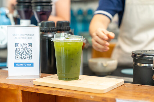 Barista serving fresh iced green tea matcha to customer at cafe counter, professional beverage drink preparation specialty coffee and tea shop, small business hospitality and takeaway drink service