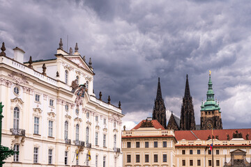 Naklejka premium Historic Prague Castle complex with St. Vitus Cathedral and palace architecture under dramatic storm clouds in Prague, Czechia.