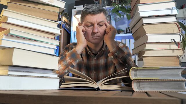 Mature Man Studying Among Stacks of Books in Cozy Home Library Room, quiet academic environment showing dedication, scholarship, personal growth and intellectual curiosity