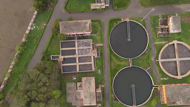 Aerial top view of wastewater treatment plant with circular clarifier tanks and sewage treatment infrastructure in Surat India