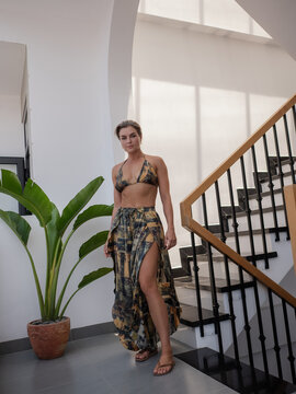 Woman models coordinated patterned resort wear with halter bikini top and flowing wide leg pants