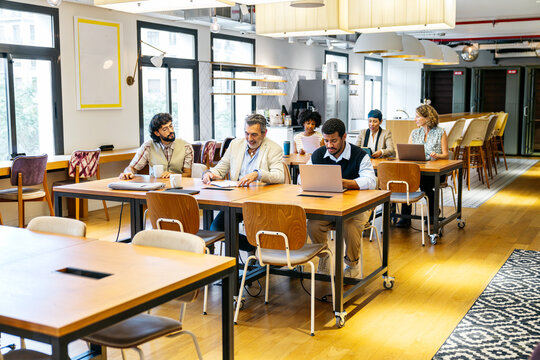 Business professionals working and discussing together in a shared office environment, fostering collaboration, and innovation