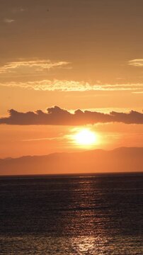 Sunset Over the Ocean with Dramatic Clouds and Golden Sky at Dusk, 4K vertical Video