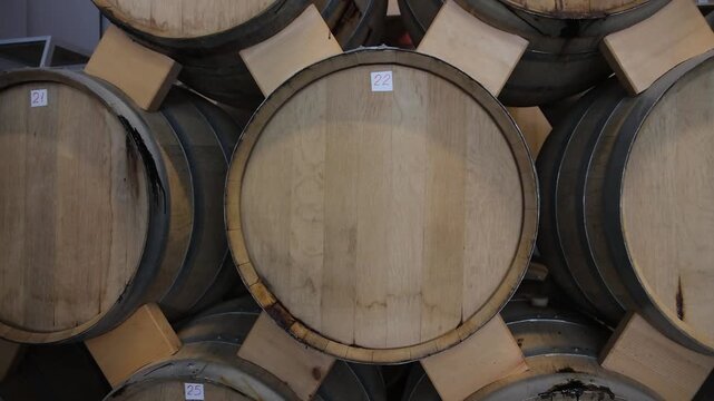 Aged Wooden Barrels Filled with Wine, Brandy or Whiskey in Historic Cellar Warehouse, Dolly Gimbal Movement Along Long Rows of Oak Casks During Alcohol Aging, Fermentation and Storage Process