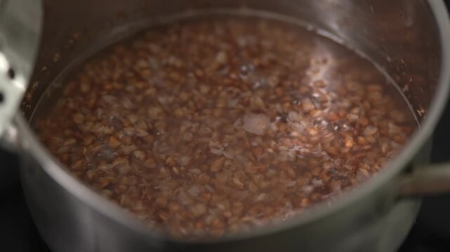 Close-up view of brown buckwheat groats boiling in hot water.