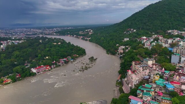 Aerial drone footage of Rishikesh during monsoon, showcasing the Ganges River, Ram Jhula, Lakshman Jhula, lush green Himalayan foothills, temples, and the scenic spiritual city of Uttarakhand.