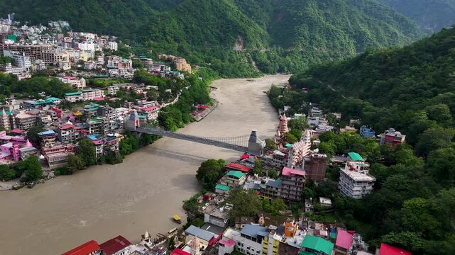 Aerial drone footage of Rishikesh during monsoon, showcasing the Ganges River, Ram Jhula, Lakshman Jhula, lush green Himalayan foothills, temples, and the scenic spiritual city of Uttarakhand.