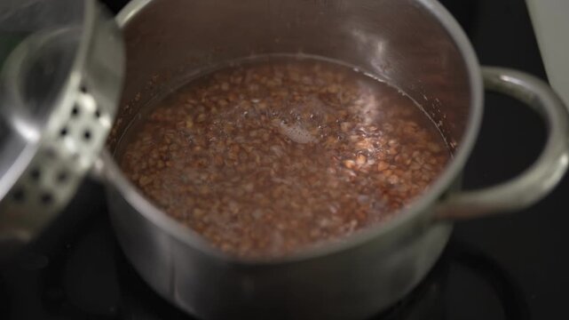 Close-up view of brown buckwheat groats boiling in hot water.