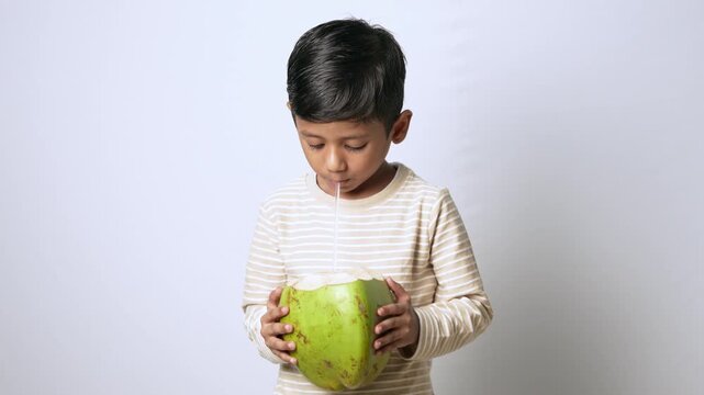 Indian boy drinking coconut water. Child enjoying fresh tropical fruit drink.