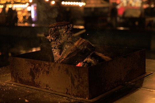 Firewood burning in a metal container at a night market during winter time