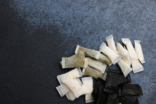 Variety of snus pouches and nicotine pads arranged on a dark surface during daytime