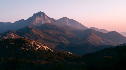 Obraz premium Sunrise bathes rugged mountain peaks in warm light casting long shadows across layered ridges and rocky slopes