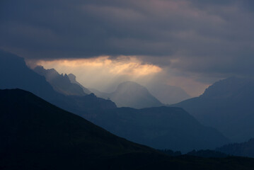 Breathtaking mountain landscape featuring golden sun rays breaking through heavy dark clouds. Perfect for conceptual themes of hope, resilience, and natural beauty backgrounds. © marcodenaro