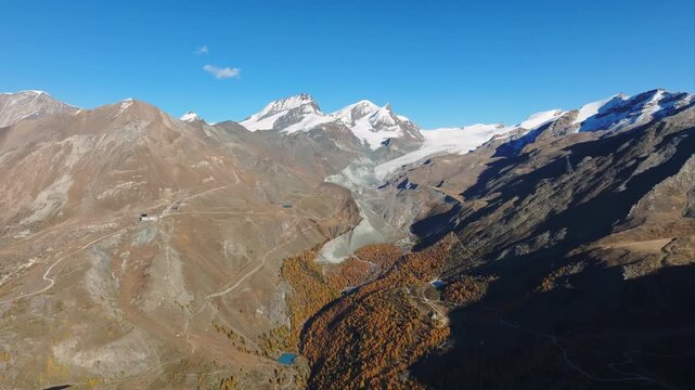 Aerial drone view of a mountain valley with dense forest surrounded by high alpine peaks. Travel and nature landscape concept.