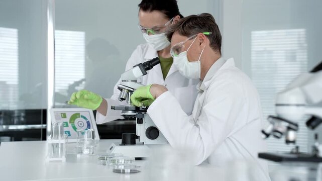 Scientific team analyzing samples in a modern laboratory, focusing on research and development for health care solutions, using advanced microscopes and digital data for discovery and progress