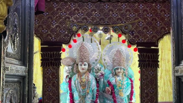 Sacred idols of Lord Rama and Goddess Sita displayed beneath an ornate temple arch, adorned with colorful garments and floral garlands. The image reflects divine blessings, eternal devotion