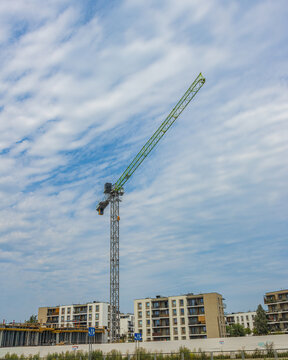 Construction crane operating at residential building site against cloudy sky