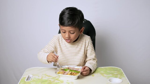 Indian boy eating healthy food from container. Child enjoying a nutritious meal at home.