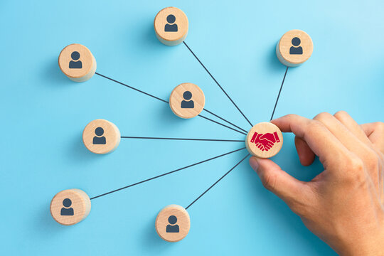 Business partnership and networking concept, hand placing red handshake icon connected to people blocks