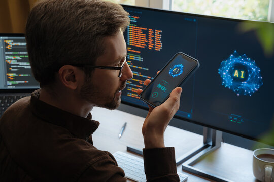 Over-the-shoulder view, of man holding smartphone, talking with AI chatbot app, asking questions, using artificial intelligence assistant for work and daily tasks on phone and computer. Space for text