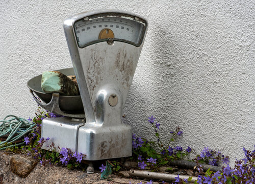 Vintage mechanical weighing scale with metal bowl in rustic outdoor setting