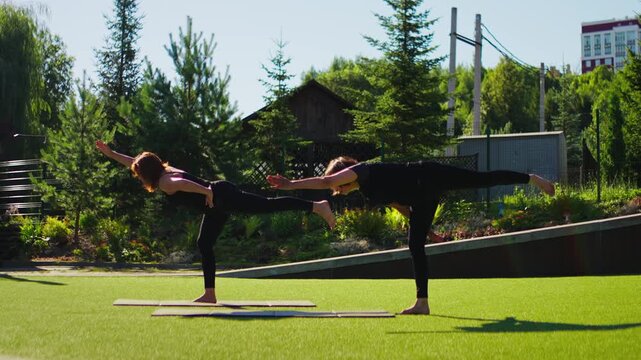 Elderly women practicing slow motion Pilates together on yoga mats in a sunny outdoor garden park, focusing on balance, posture, and gentle mindful movement