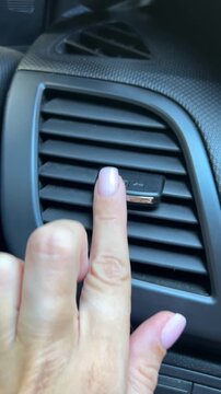 Hand opening a car air vent by sliding the airflow control 
