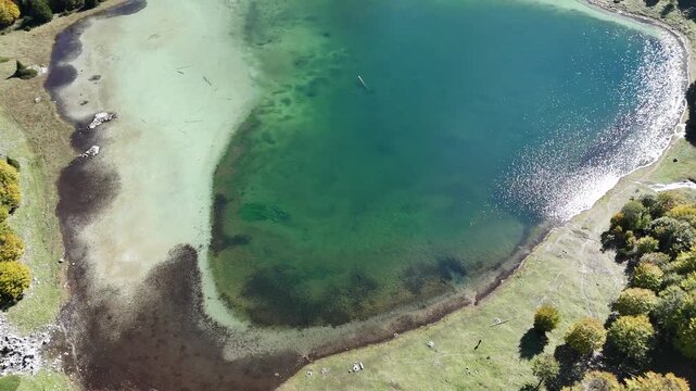 Aerial flyover and pan up revealing heart shaped Trnovacko Lake in Montenegro mountains