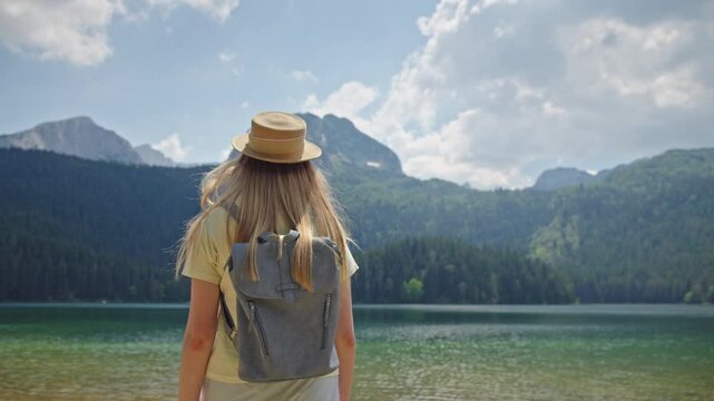 Young woman with backpack enjoying the panoramic view of Black Lake in Durmitor National Park, Montenegro. Summer mountain landscape 