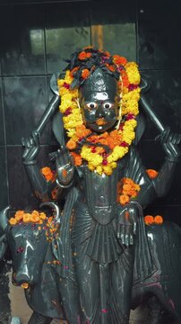 Lord Shani Dev adorned with vibrant marigold flower garlands inside a Hindu temple. Revered as the deity of justice, karma, discipline, and righteousness, Shani Dev blesses devotees with protection