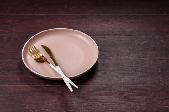 An empty round ceramic plate on a dark, textured brown background. An empty round plate
