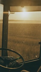 Obraz premium Golden hour sunlight through tractor window over field, concept of agriculture and farming