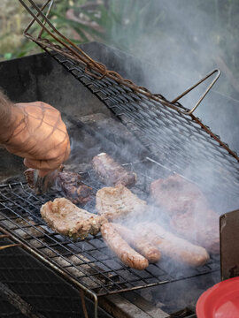 Carne e salsicce cotte su barbecue all'aperto avvolto dal fumo