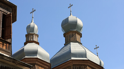 Architectural detail of wooden church domes and crosses under a clear blue sky in Tulyntsi, Kyiv Oblast, Ukraine. © Юрій Борисов