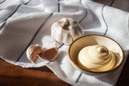 Mayonnaise with Fresh Garlic on Kitchen Towel and Wooden Table