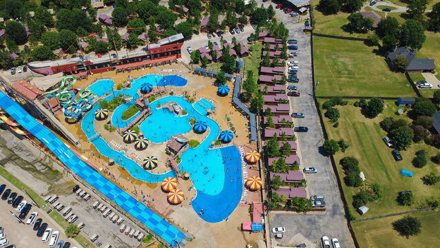 Water resort grounds near Fort Worth showcase lazy river pools. Pirate ship lodge, guest cabins, mat racer slides highlight resort accommodations under brilliant summer weather, Burleson, TX