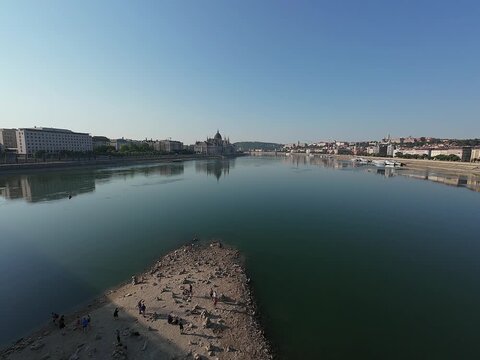 Low water level of the Danube river in Budapest at sunrise, featuring the Liberty Bridge and the uncovered Inseg Rock, and the Margit bridge and the island. 02.08.2026.