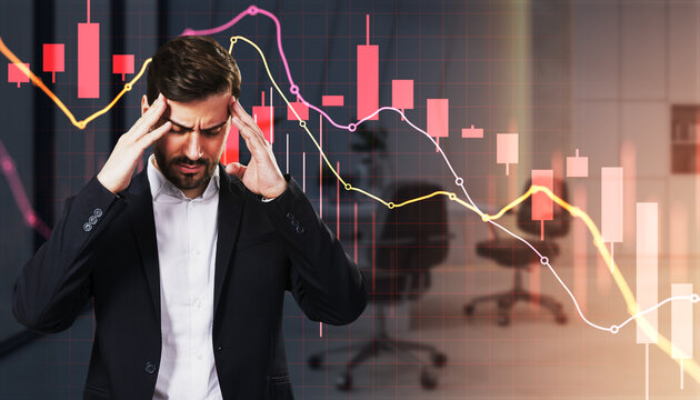 Stressed businessman facing falling financial market charts and economic uncertainty in a dark office background, symbolizing investment crisis.