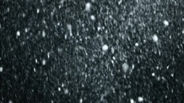 White decorative snowflakes falling on a solid black background