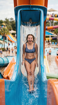 Excited young woman screaming with joy on a waterpark trapdoor drop slide
