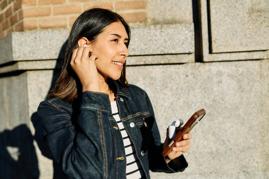 Portrait of a happy young woman tourist travelling or student or a businesswoman entrepreneur, using a smartphone phone or texting outdoors in front of a modern urban background