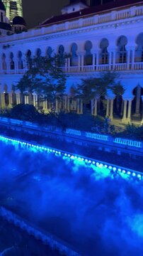 Night view of the River of Life (Kolam Biru) featured with blue neon lighting, mist, and fountain show near Masjid Jamek and Merdeka Square in Kuala Lumpur, Malaysia. 