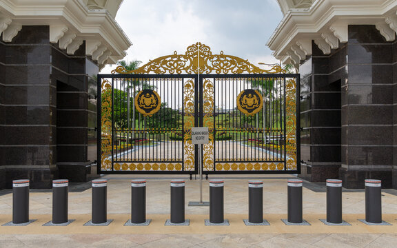 Decorative golden gates featuring the Malaysian coat of arms at the Istana Negara, the official residence of the King, in Kuala Lumpur, Malaysia, with security bollards in the foreground