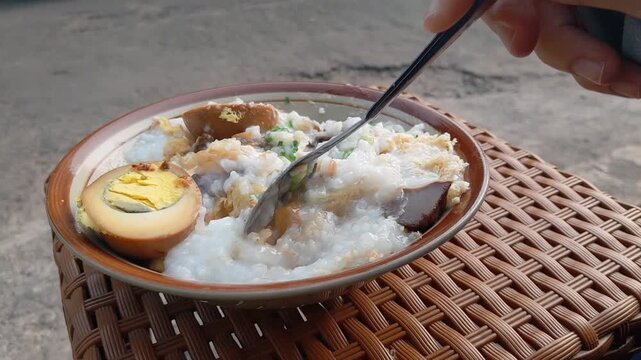 Chicken porridge with a full complement of toppings: shredded chicken, a hard-boiled egg, chicken liver and gizzard, and a sprinkle of peanuts. A favorite Indonesian street food for breakfast