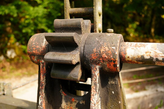 Close-up of a weathered rusty iron gear and pinion mechanism on a historic water gate dam in Slovenia.