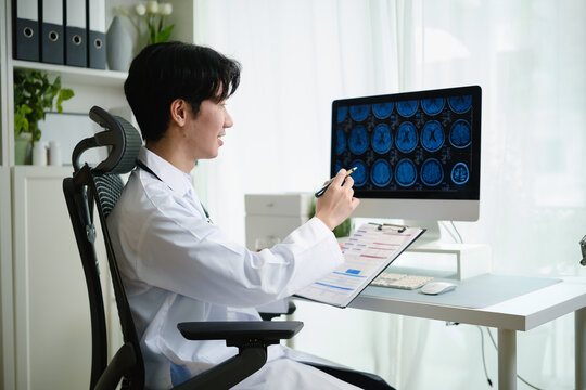 Doctor analyzing brain scan images on a computer monitor in a modern medical office.