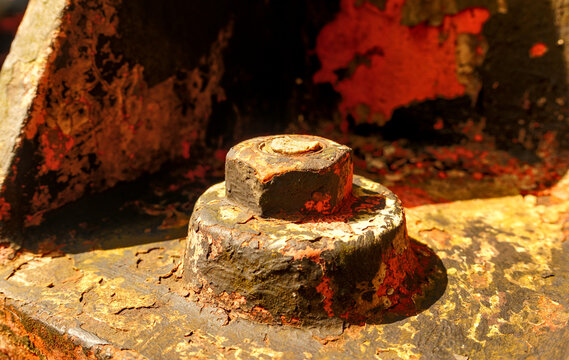 Macro view of a heavy rusted bolt and nut with peeling paint on vintage dam machinery along the Idrijca River, Slovenia.