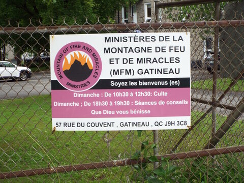 Gatineau, Quebec, Canada &ndash; June 11, 2026: A bilingual sign for "Minist&egrave;res de la Montagne de Feu et de Miracles MFM Gatineau" hangs on a chain-link fence on Chem. Eardley.

