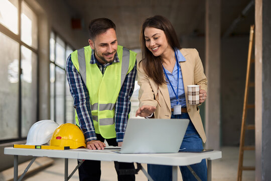 Female architect and building contractor using laptop at construction site